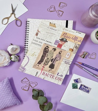A Lilac Surface Adorned with Heart-Shaped Paperclips, A Pair of Scissors, Stationary Items, and a Scrapbook Page about Haute Couture